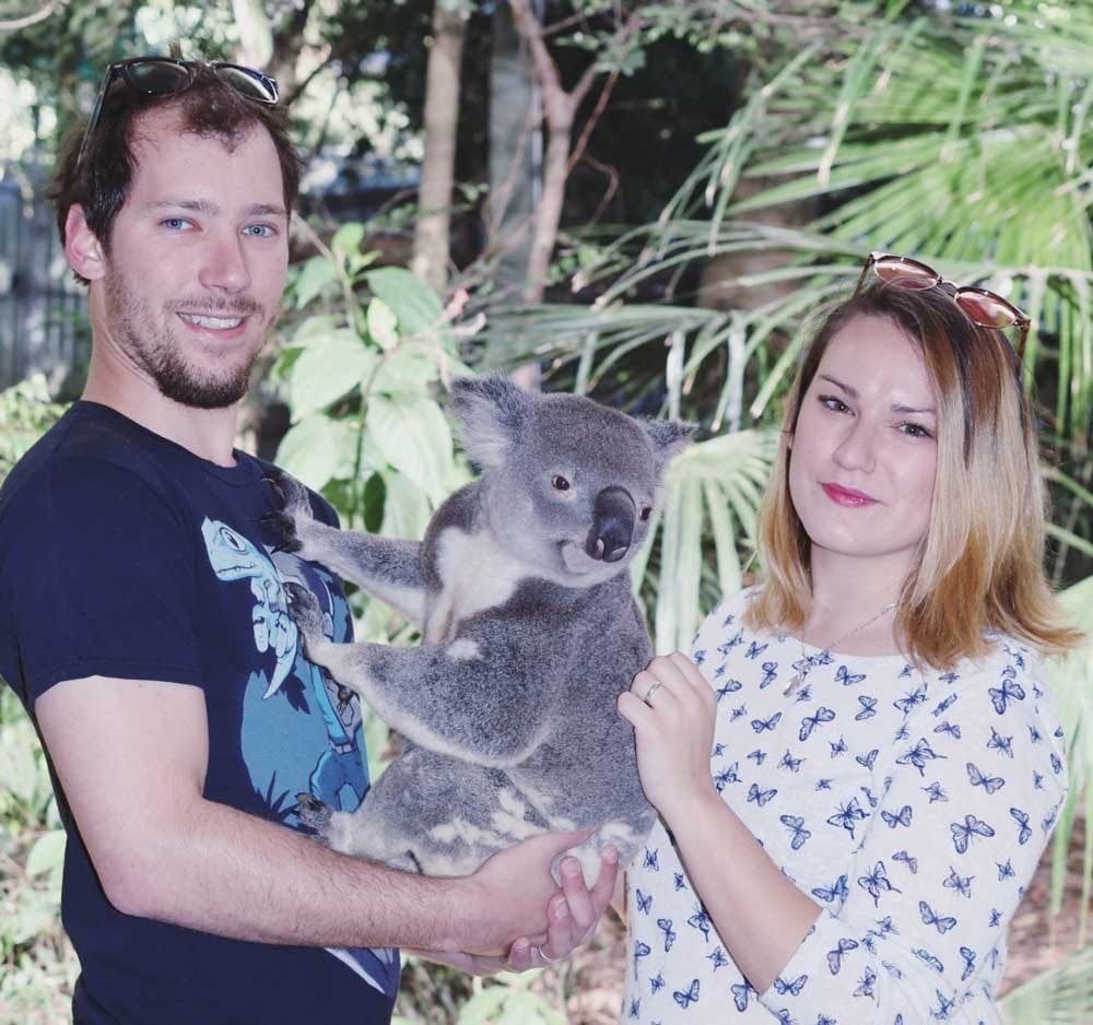 chica y chico sujetando un koala. Los dos miran a cámara sonrientes
